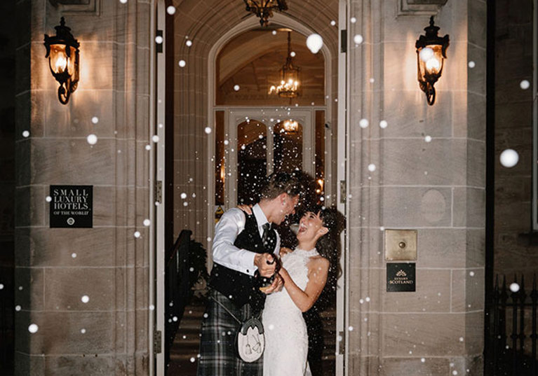 Nighttime champagne spray bride and groom outside Crossbasket Castle